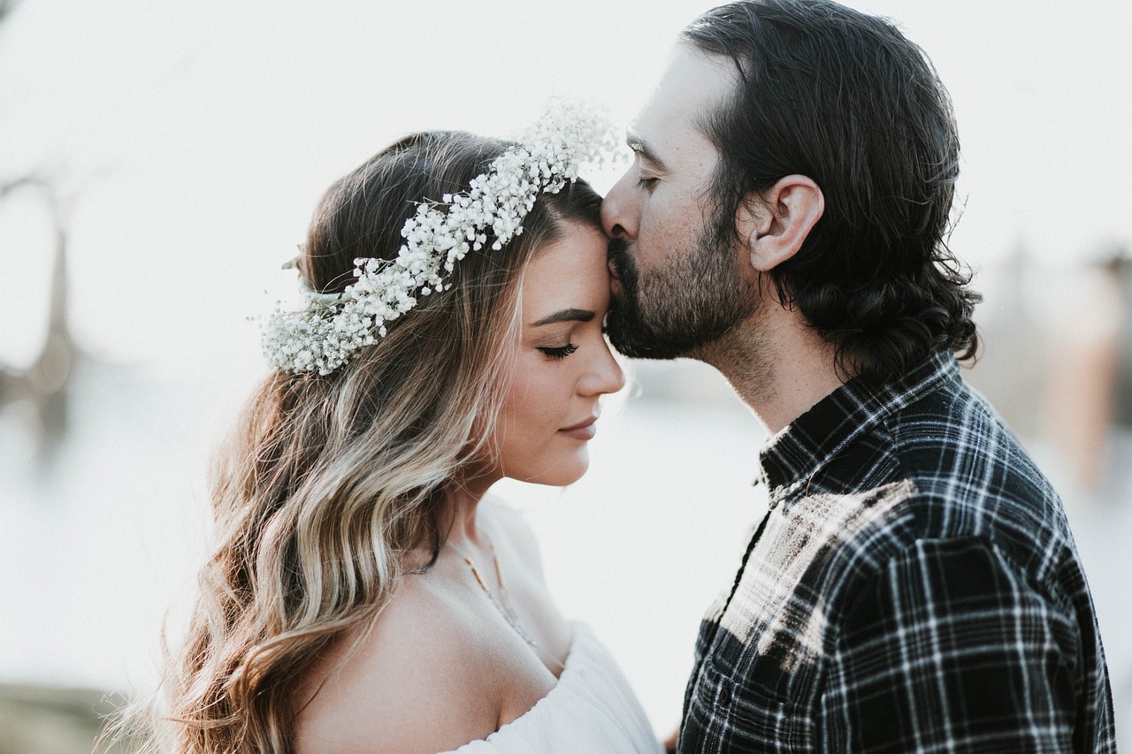 man kissing woman's forehead