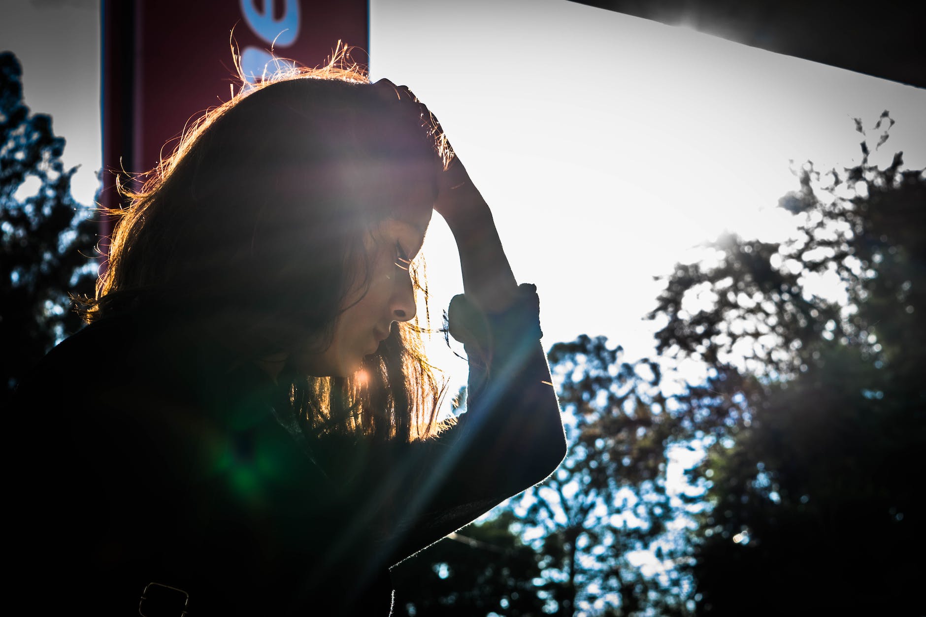 sad woman looking down and pushing hair back with hand
