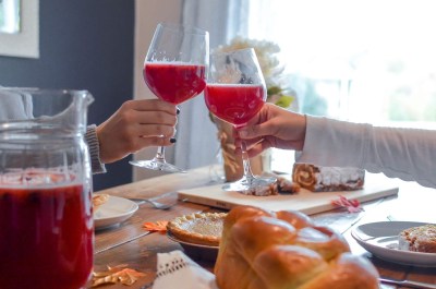 two hands cheering autumn season food two people cheering glasses with apple cider and a table spread with apple pie and autumn foods