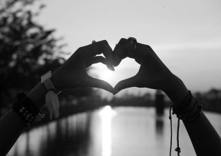heart with hands love two hands with bohemian bracelets making a heart sign with sun shining through it