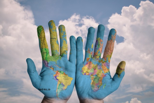 planet earth hands hands with world maps on them reaching towards sky
