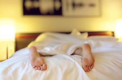 camera angle facing someone under bedsheets with feet facing viewer