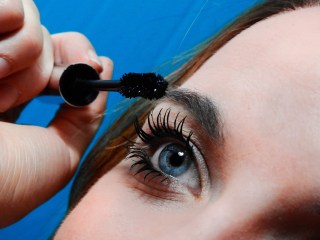 closeup of young woman putting on mascara