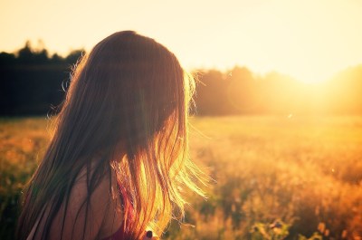 sunlight outlining and crowning the hair of a girl looking down bringing hope