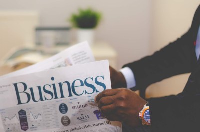 black man's hands holding a Business newspaper