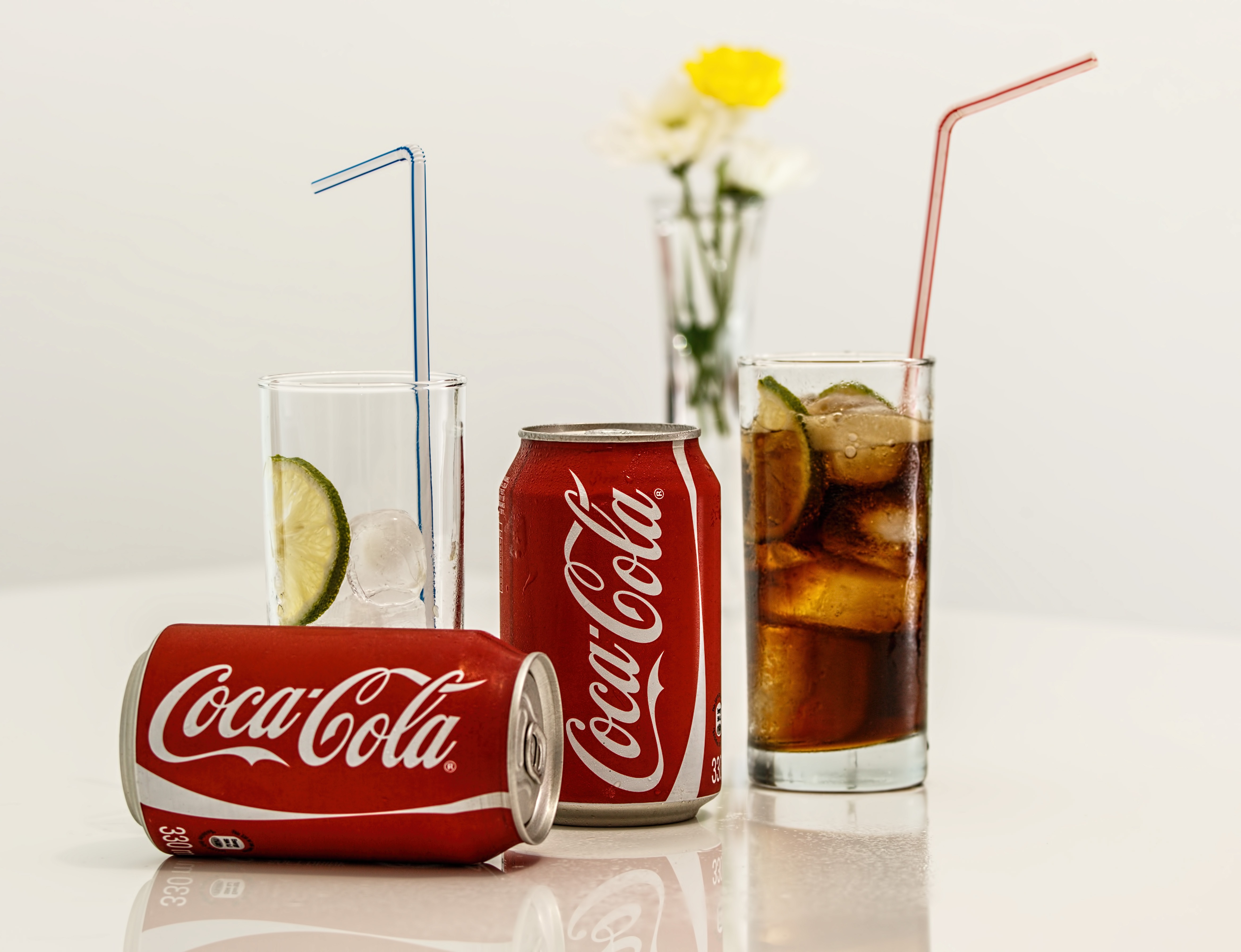 coca cola cans with glass drinks beside them